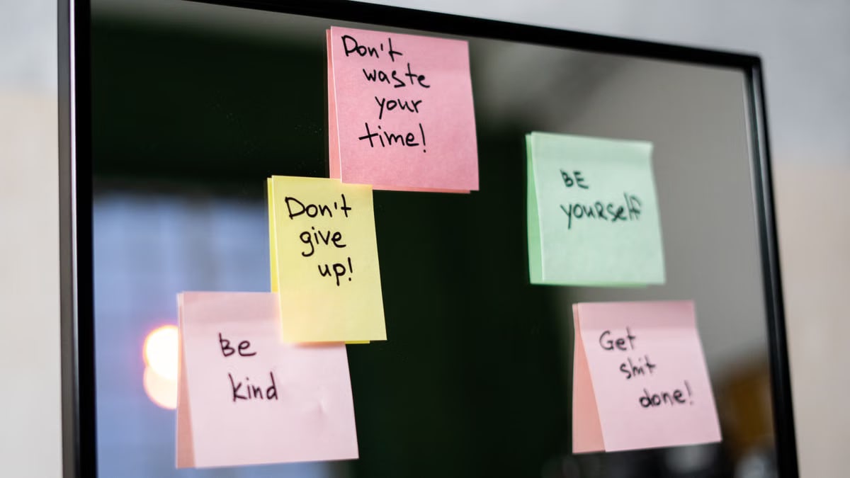 Colorful sticky notes with motivational messages on a mirror reflecting positivity.